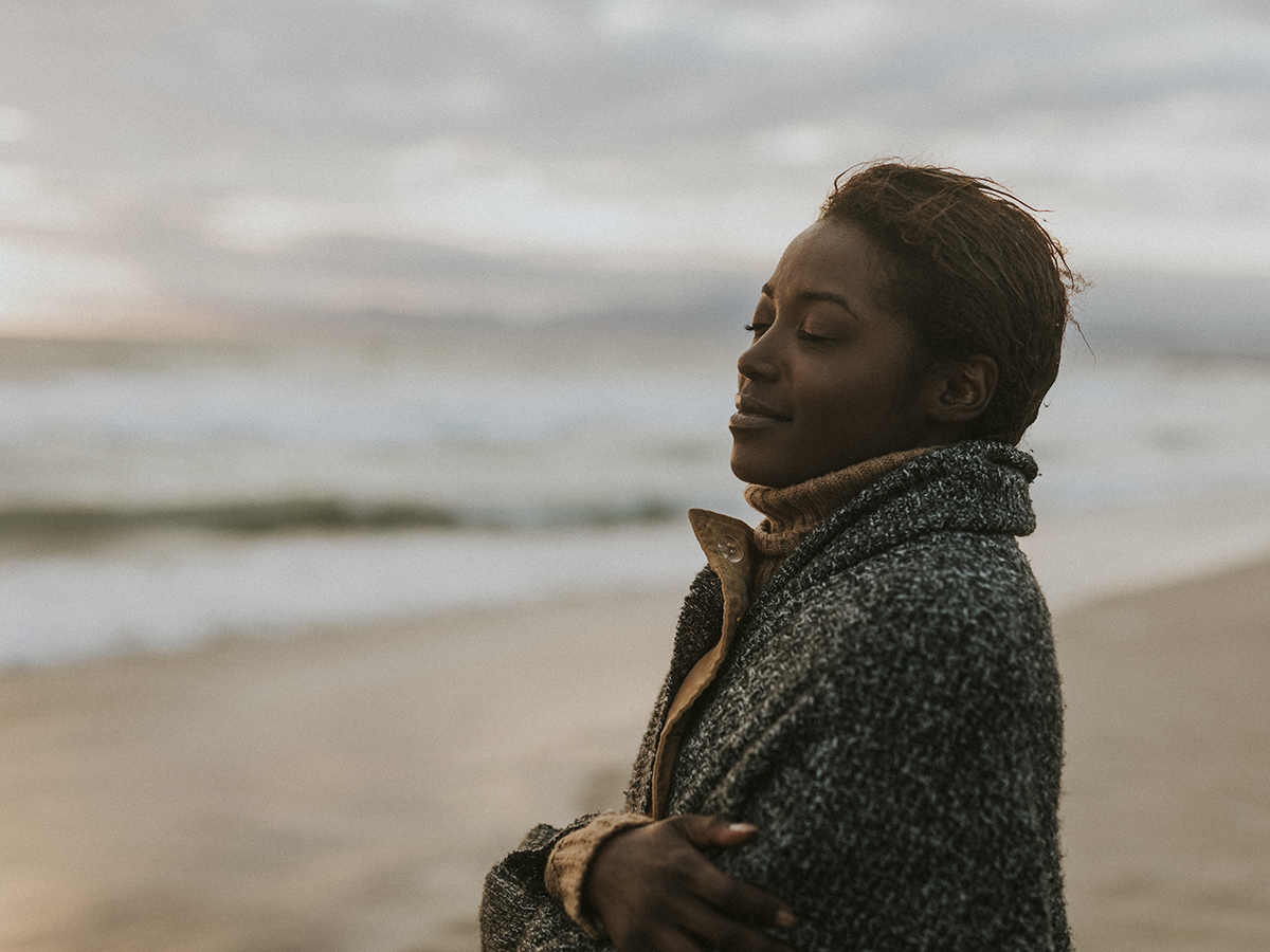 A woman smiling as she looks out over a beach in warm sunset light