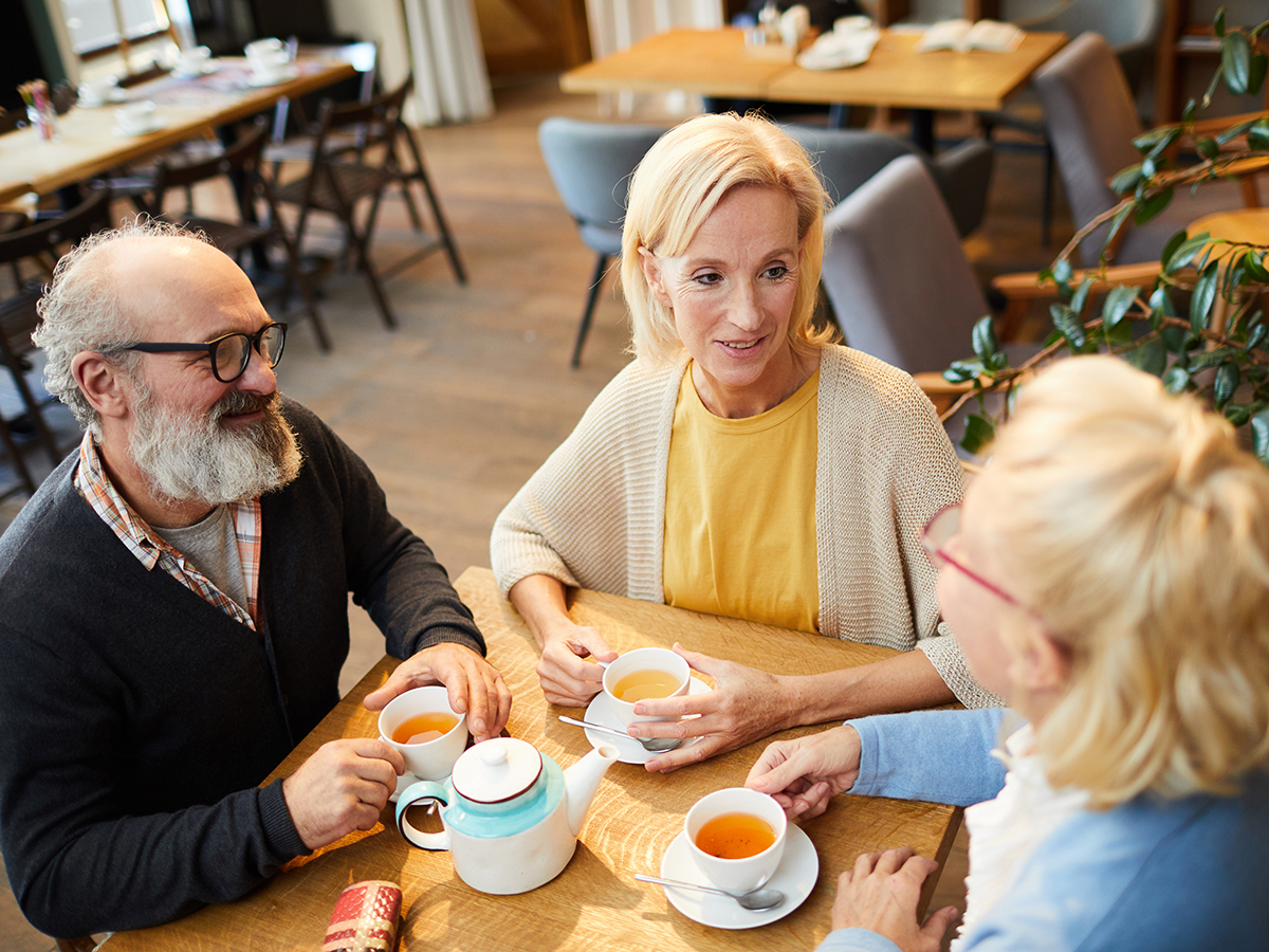 Two women and a man sitting in a cafe, talking together